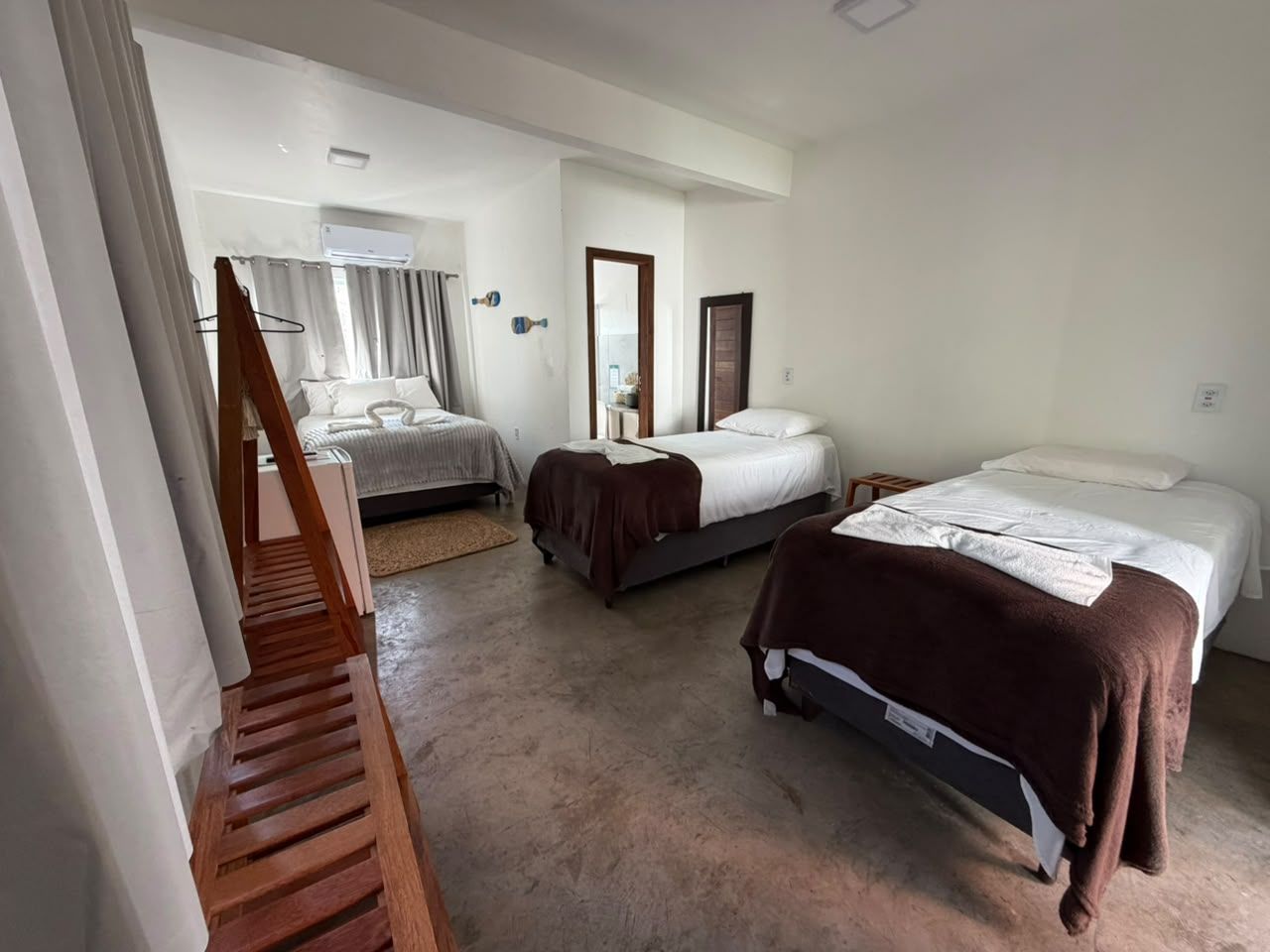 A hotel room with two beds, a wooden ladder, a mirror, and a small table.