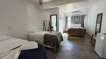 A room with two beds, a refrigerator, and a window with curtains.