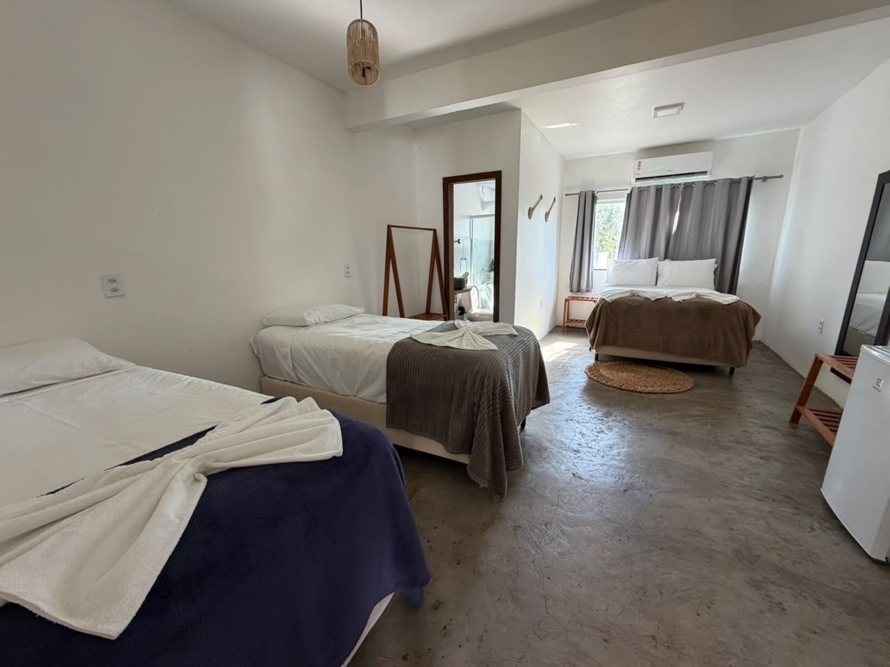 A room with two beds, a small table, and a refrigerator.