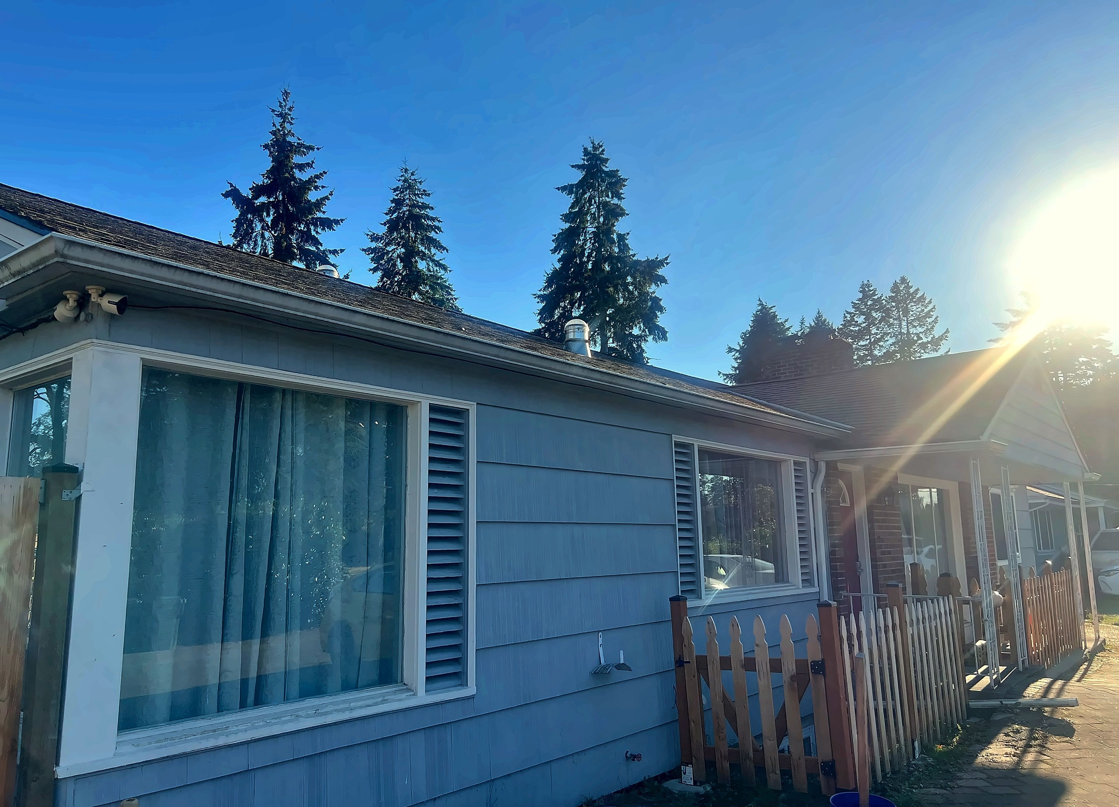 A mobile home with a large window, a wooden fence, and a clear sky.