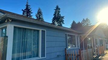 A mobile home with a large window, a wooden fence, and a clear sky.