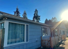A mobile home with a large window, a wooden fence, and a clear sky.