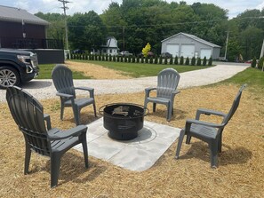 A patio with four Adirondack chairs and a black fire pit on a mat. - Welcome to Pymatuning Lake Lodge - a 3 Bedroom, 2 Bathroom getaway! (Pymatuning Central)