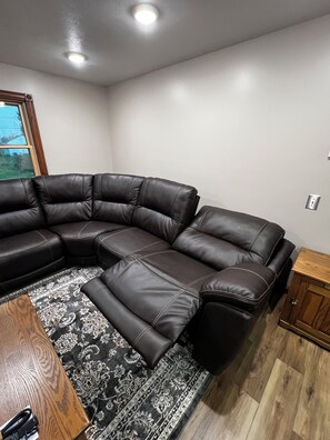 A sectional sofa in a room with a wooden cabinet and a patterned rug. - Welcome to Pymatuning Lake Lodge - a 3 Bedroom, 2 Bathroom getaway! (Pymatuning Central)