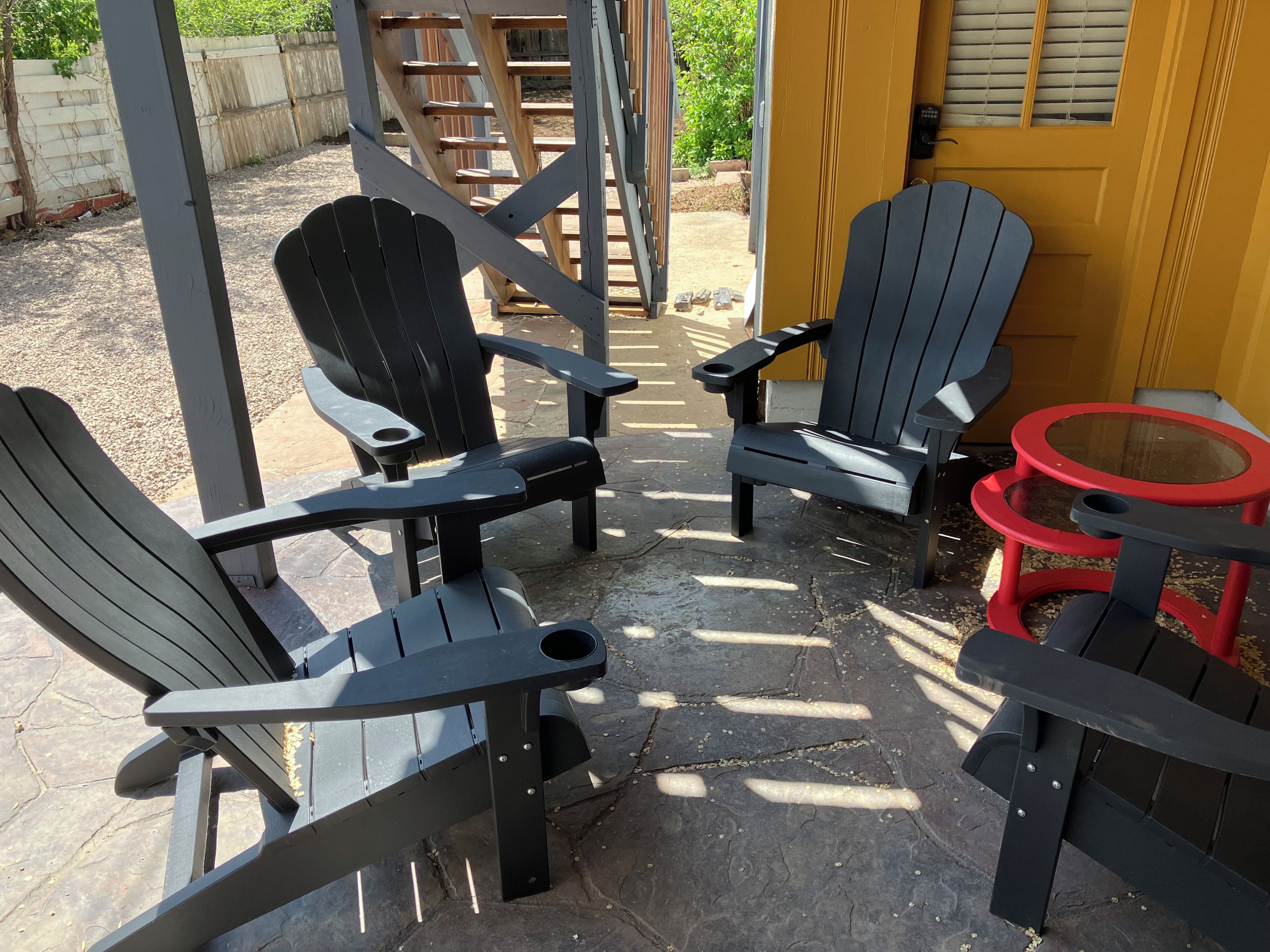 A patio area with two Adirondack chairs and a small round table.