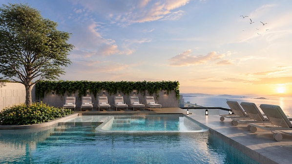 Ein Dachpool mit Infinity-Kante, Liegestühlen und Blick auf den Sonnenuntergang über dem Meer.