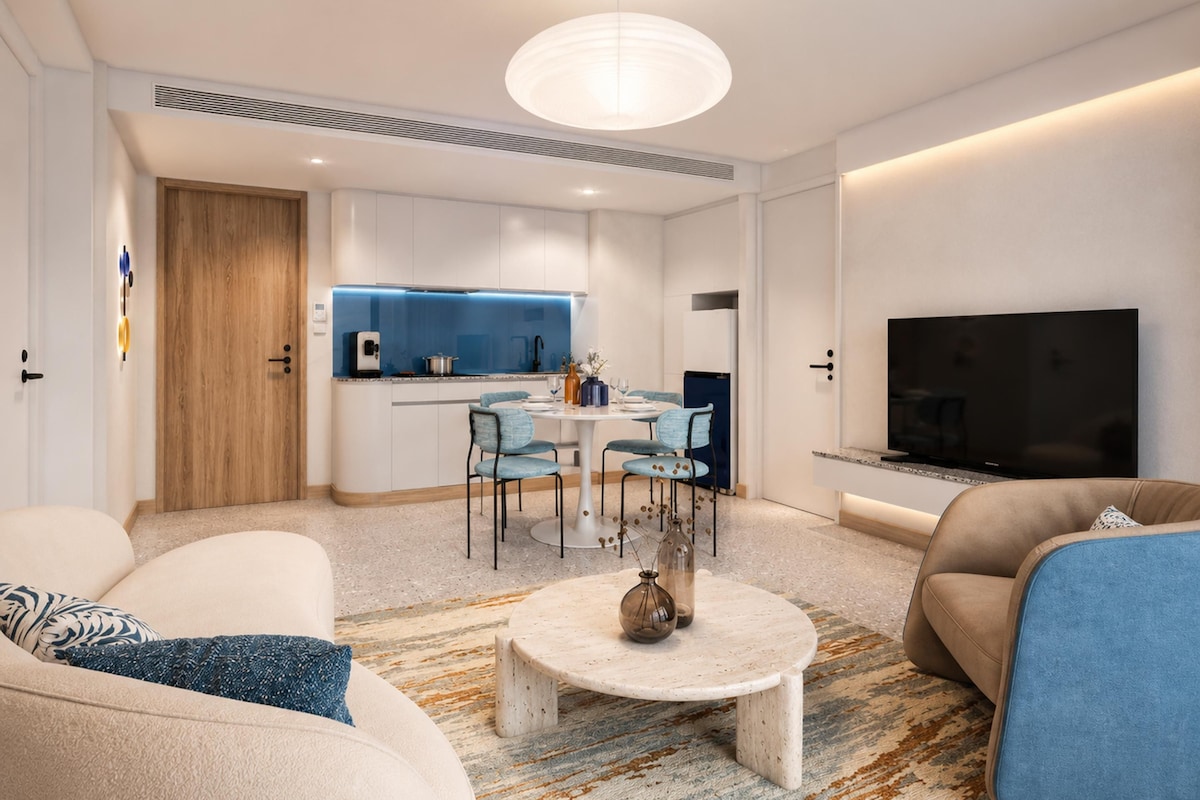 Ein modernes Wohnzimmer mit Essbereich, einer Küche mit blauen Akzenten und einem Flachbildfernseher.