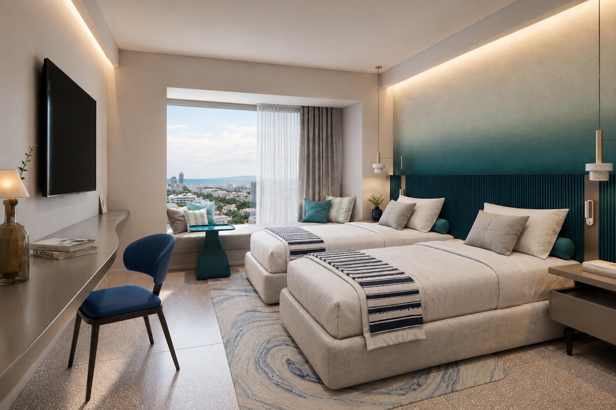 Ein Hotelzimmer mit einem großen Bett, einem Einzelbett, einem Schreibtisch, einem Sessel und Blick auf die Stadt.