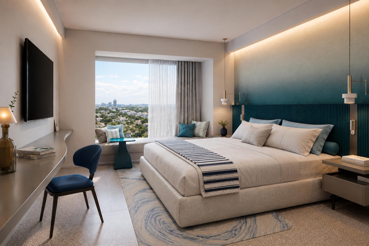 Ein modernes Hotelzimmer mit einem großen Bett, einem Schreibtisch, einem Sessel, einem Fernseher und Blick auf die Stadt.