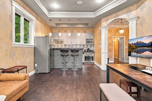 A modern kitchen with a central island, bar stools, and a dining table. - Tranquil 2-bedroom house in charming Surrey perfect for relaxing stays (Surrey)