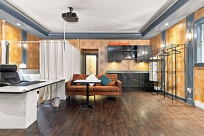 Una sala moderna con sofá, una mesa de comedor y una zona de cocina con microondas y armarios.