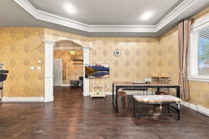 A spacious room with a dining area, a large painting, and a clock on the wall. - Tranquil 2-bedroom house in charming Surrey perfect for relaxing stays (Surrey)