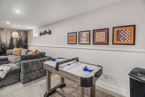Un salon avec une table de baby-foot, un canapé et un mur orné de tableaux.