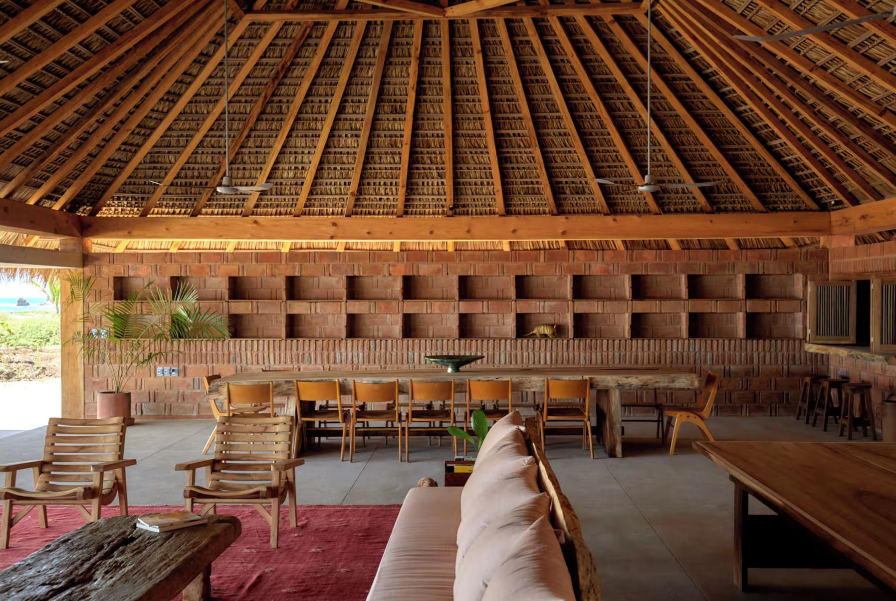 A spacious indoor area with a high ceiling, wooden furniture, and a brick wall with shelves.