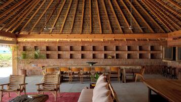 A spacious indoor area with a high ceiling, wooden furniture, and a brick wall with shelves.