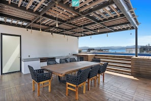 Un espace de restauration en plein air avec une table et des chaises en bois, un bar et une vue sur les montagnes.