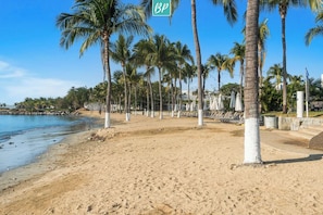 A beach with palm trees, a sandy shore, and a clear blue sky. - Villa 78 | 2 Private Pools + Beach Club Access (Cruz de Huanacaxtle)