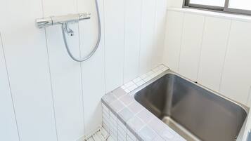 A small bathroom with a shower, a window, and a sink.