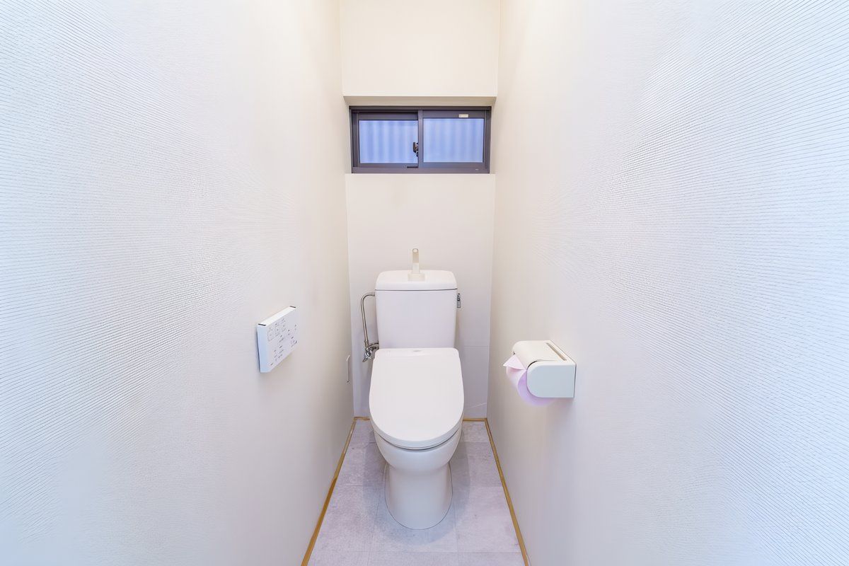 Un baño pequeño y funcional con inodoro, ventana y secador de manos.