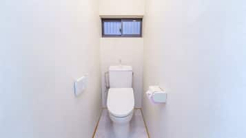 Un baño pequeño y funcional con inodoro, ventana y secador de manos.