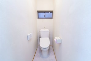 Ein kleines, kompaktes Badezimmer mit Toilette, Fenster und Handtrockner.