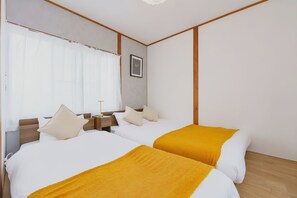 Ein Hotelzimmer mit zwei Betten, einem Nachttisch, einem gerahmten Bild an der Wand und einem Fenster mit Vorhängen.