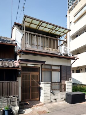 Ein Wohngebäude mit traditionellen Ziegeln, einem Balkon mit Glasveranda und einer Klimaanlage im oberen Stockwerk.