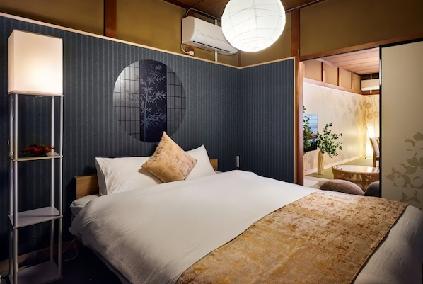 Ein Hotelzimmer mit Bett, Nachttisch, Lampe und Blick ins Freie.