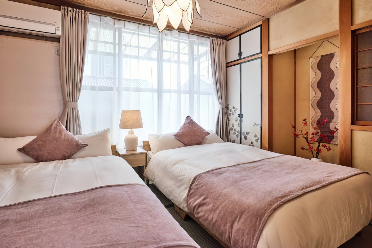 Ein Hotelzimmer mit zwei Betten, einem Vorhangfenster, einer Lampe und einer dekorativen Wandverkleidung.