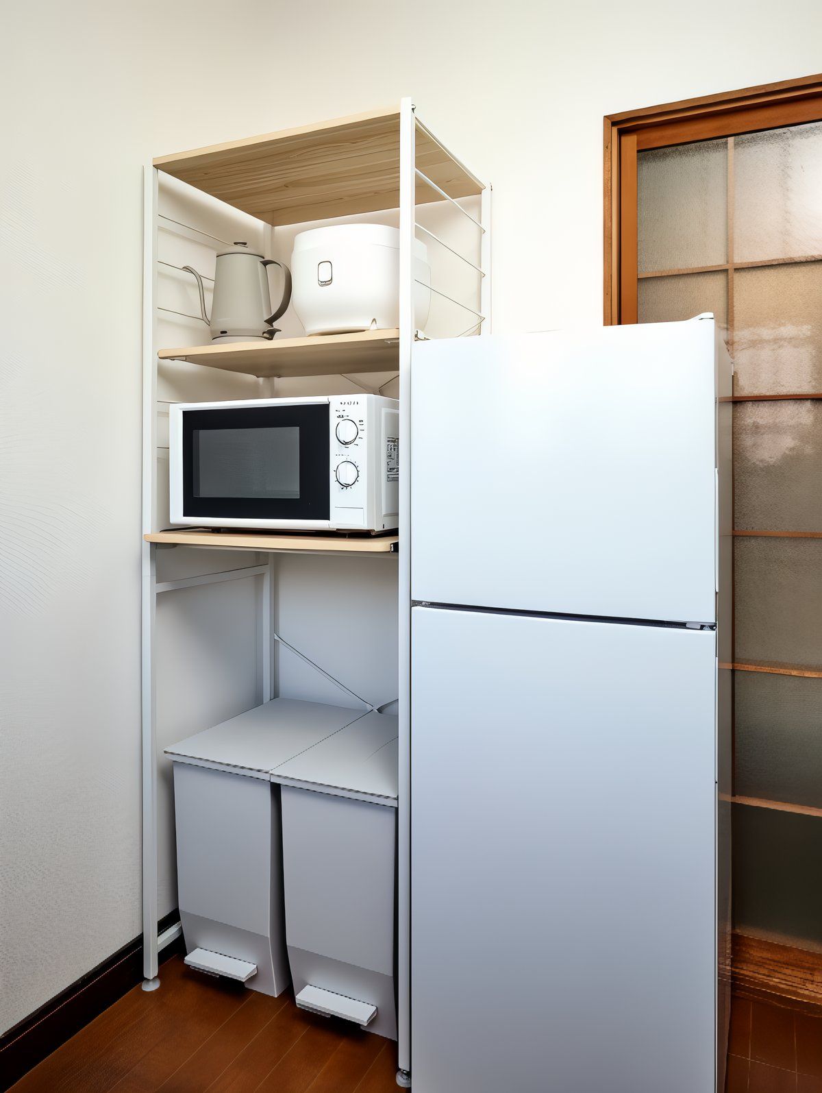 A compact kitchen with a white refrigerator, a microwave, and a kettle on a shelf.