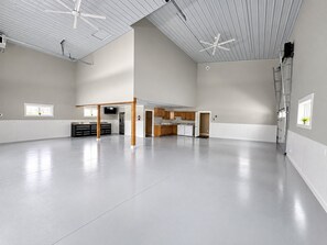 Et rummeligt, moderne køkken med hvide skabe, en central ø og en loftsvifte.