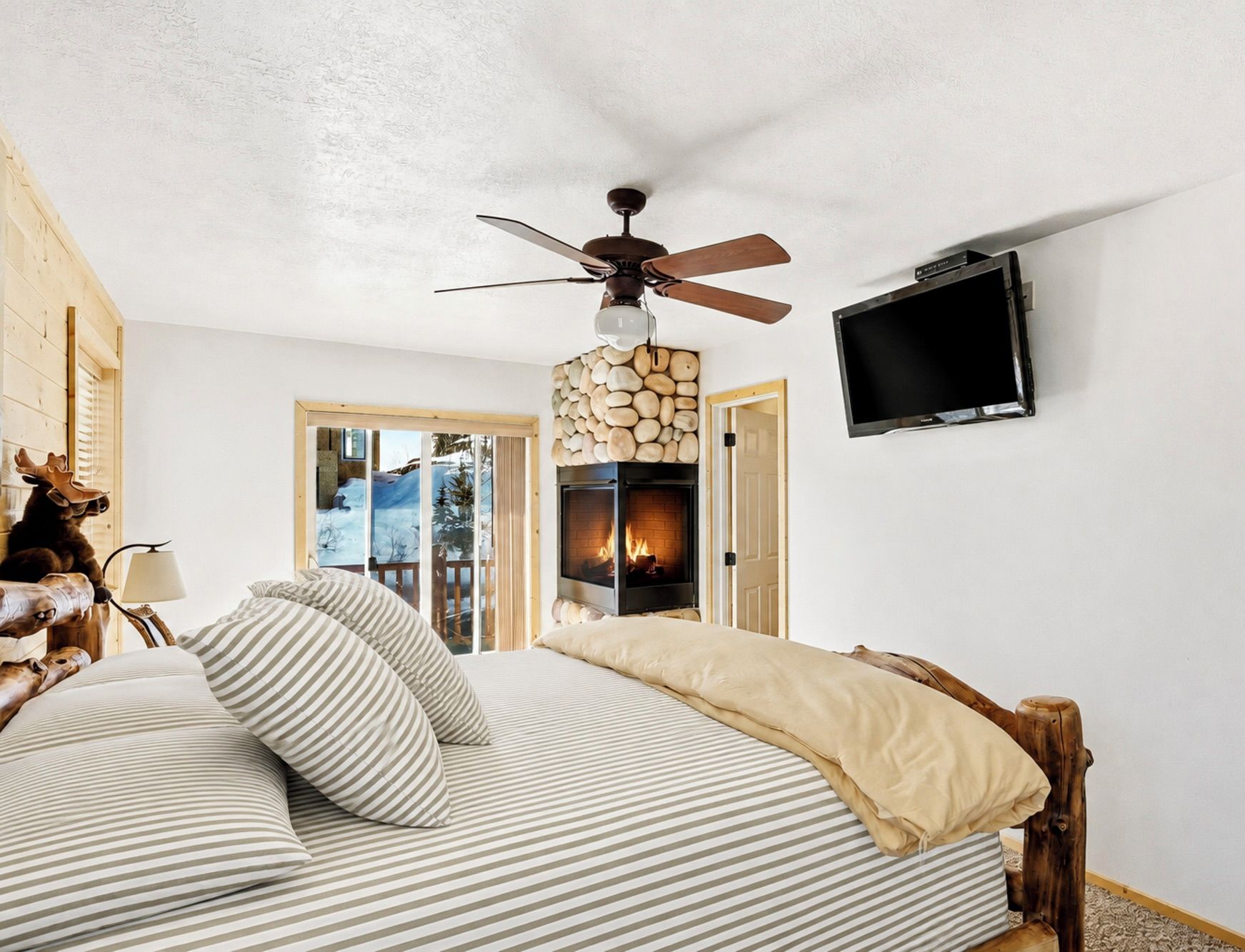 Une chambre à coucher avec un lit, un ventilateur de plafond, une cheminée et un téléviseur.