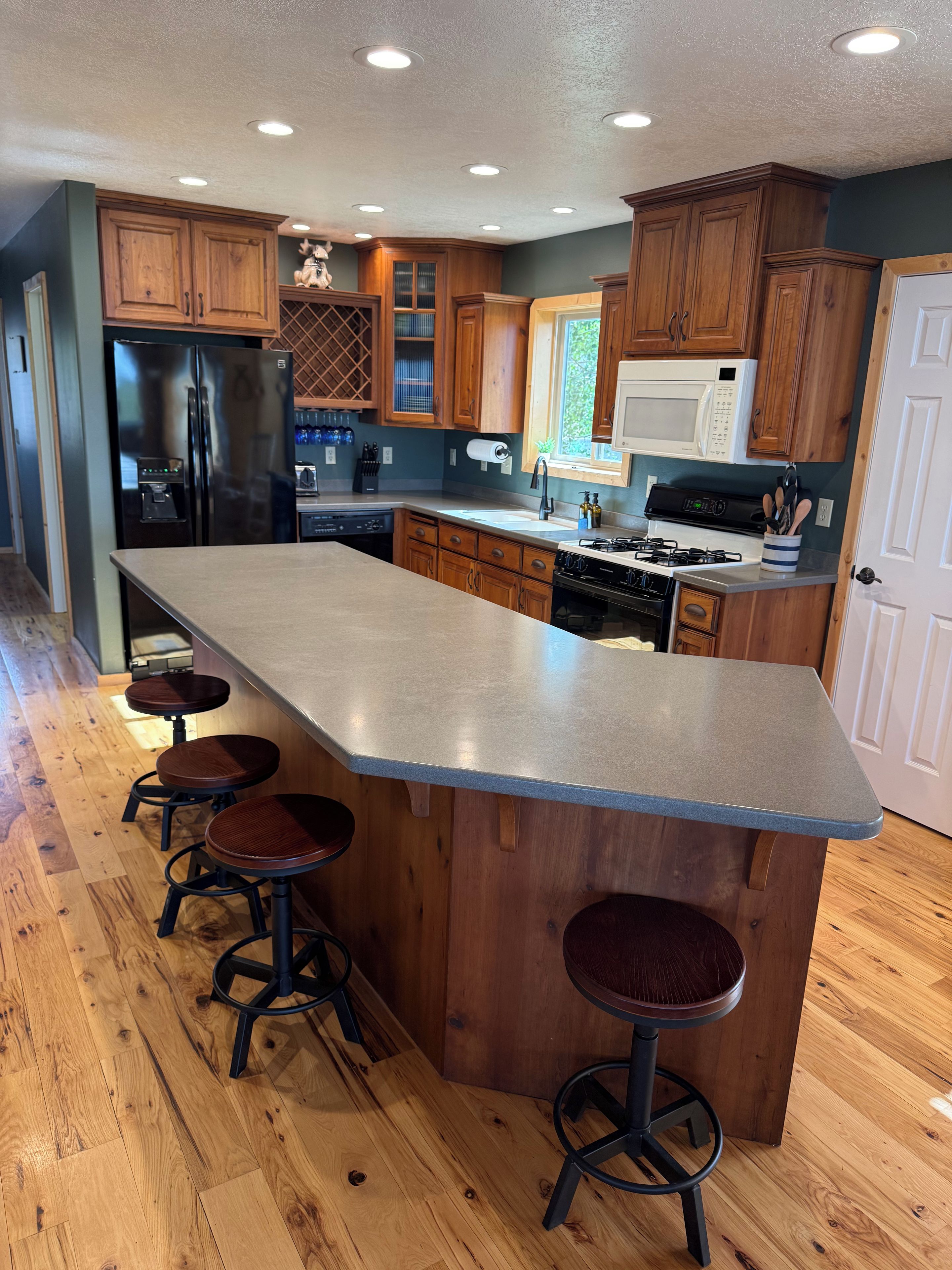 A kitchen with a central island, wooden cabinets, a stainless steel refrigerator, and a microwave.