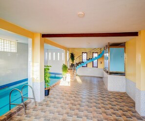 A swimming pool area with a tiled floor, a staircase, and a potted plant. - Classic Pool Villa Home Stay (Mysore)