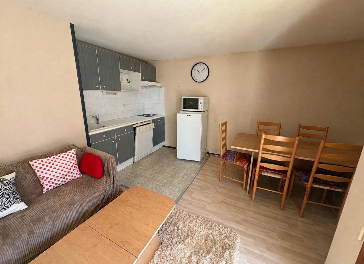 Un espacio habitable compacto con kitchenette, comedor y zona de estar.