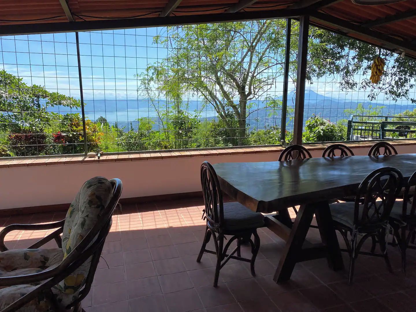A covered outdoor seating area with a view of the sea and mountains.