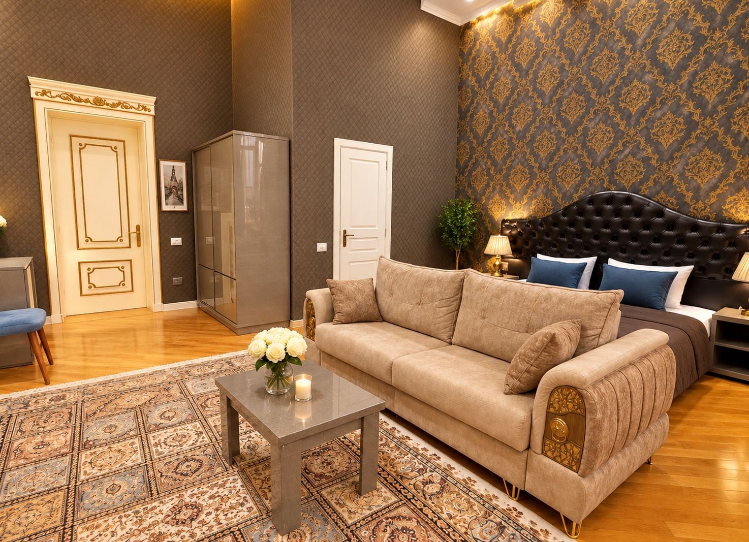 Una sala de estar con un sofá, una mesa de centro con flores, un tapete estampado y una pared decorada.