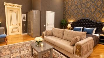 Una sala de estar con un sofá, una mesa de centro con flores, un tapete estampado y una pared decorada.