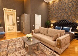 A living room with a sofa, a coffee table with flowers, a patterned rug, and a patterned wall. - Willdom Hotel (Baku)