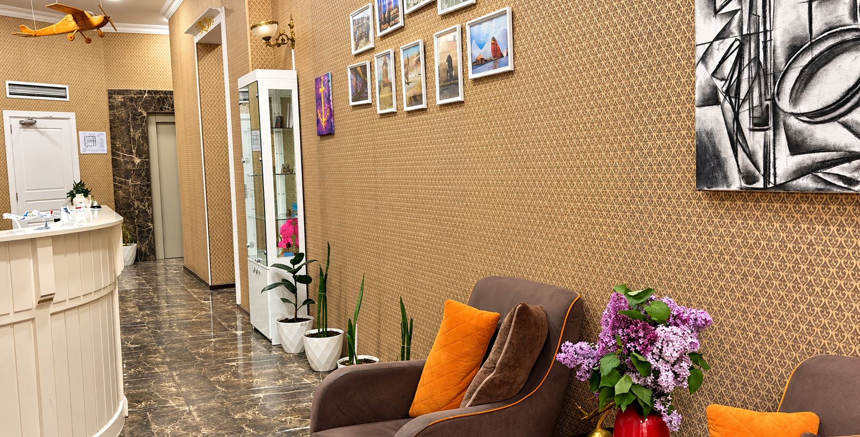 Ein Empfangsbereich mit Empfangstresen, Sitzgelegenheiten und einer Wand mit gerahmten Bildern.