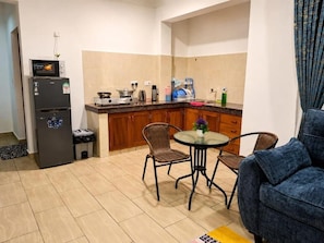 A compact kitchen with a refrigerator, stove, and dining area with chairs.