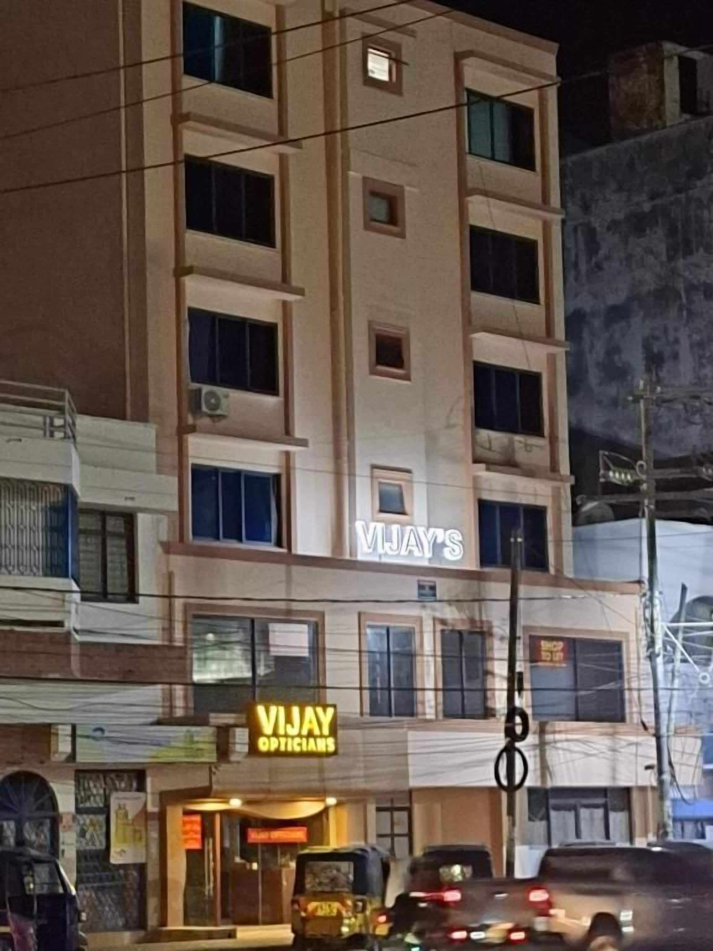 A multi-story building with a sign for 'Vijay Opticians' on the ground floor.