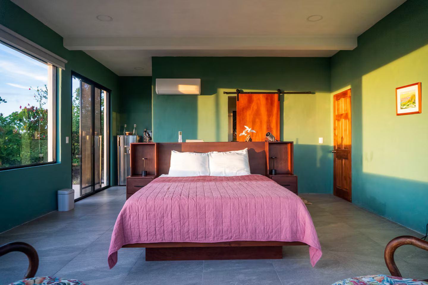 A bedroom with a large bed, a nightstand, a dresser, and a window.