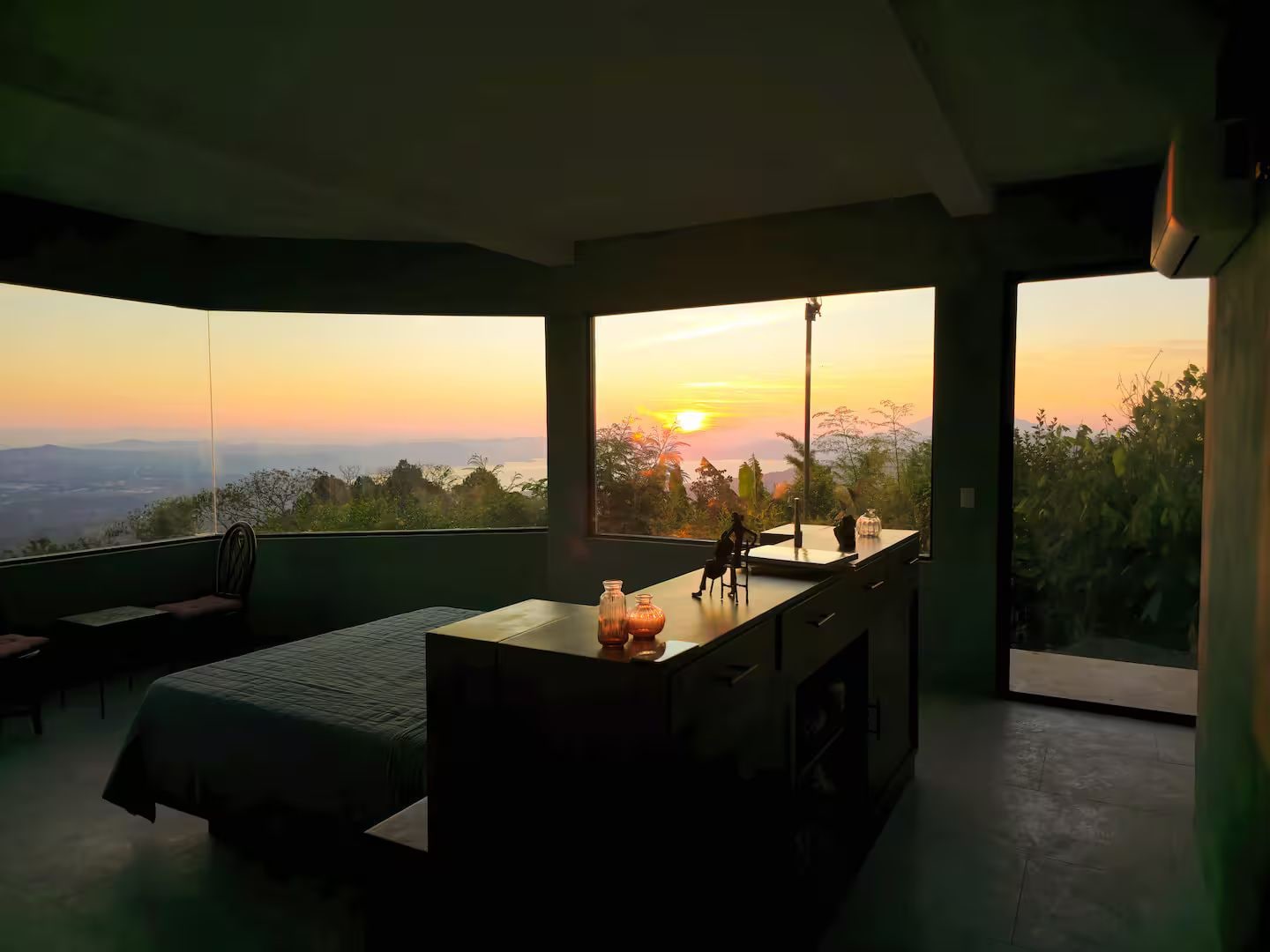 A modern bedroom with a large window, a bed, a desk, and a chair.