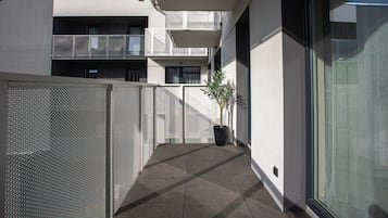 Un bâtiment moderne doté d’un balcon, d’un pot de fleurs et d’une clôture en treillis métallique.