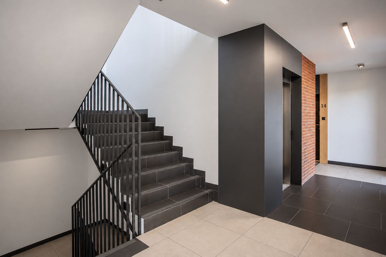 Un interior moderno con una escalera, un techo plano y una puerta marcada con el número 14.