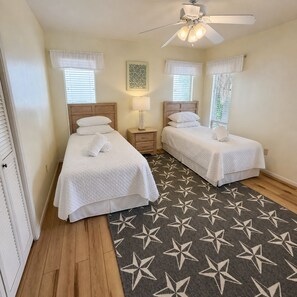 A hotel room with two beds, a ceiling fan, and a star-patterned rug. - Beachfront Home on Anna Maria Island! (Anna Maria Island)