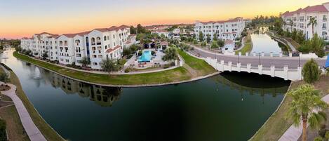 A residential area with a swimming pool, a bridge, and a canal reflecting the buildings.