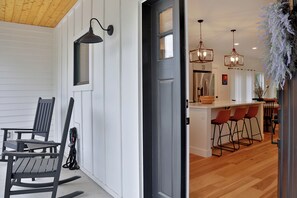 A modern kitchen with bar stools, pendant lighting, and a wooden floor. - Fir Haven Farmhouse - Stylish 3BR Escape on Whidbey (Freeland)