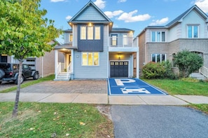 A two-story residential building with a garage and a parking space marked with a wheelchair accessibility symbol. - Minutes to Thermëa Spa, Hwy 401, GO Train & Golf (Ajax)